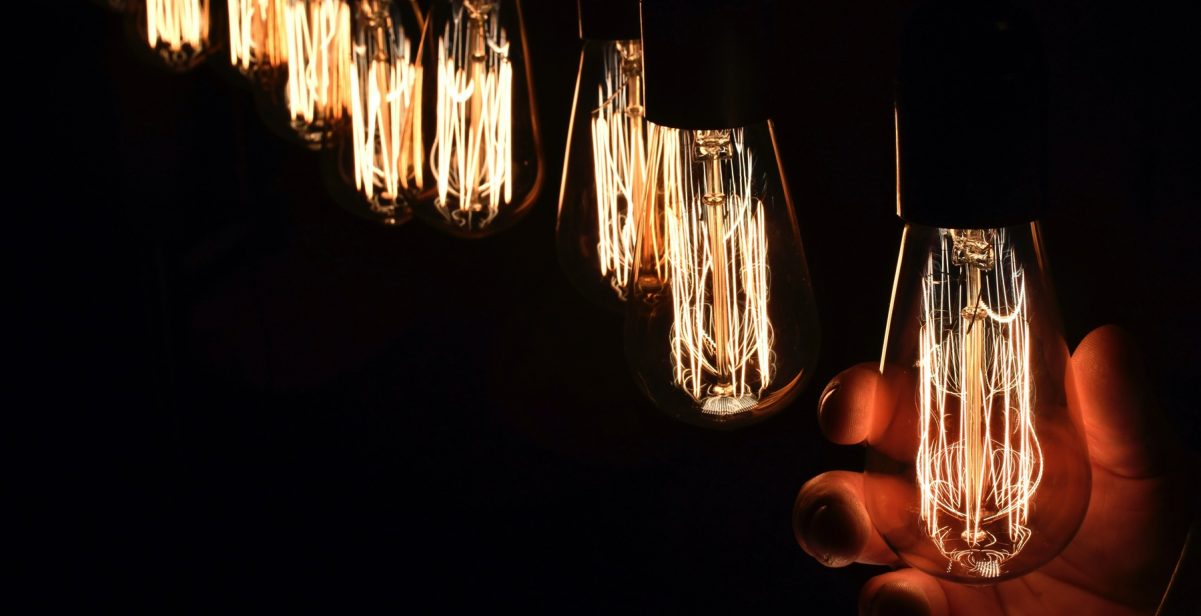 A row of filament style LED lightbulbs with a hand holding one of them