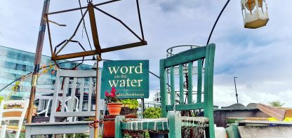 Blue chair, clear sky, sign saying Word on the water
