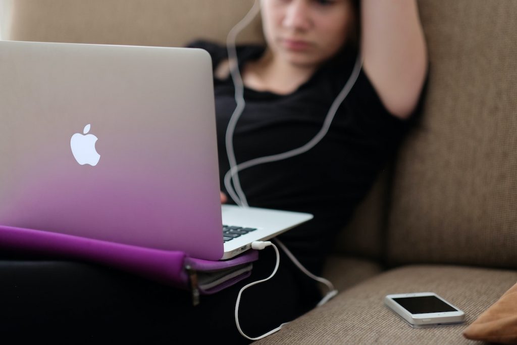 Girl with headphones looking at Apple laptop