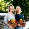 Two women with baskets of colourful vegetables