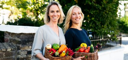Two women with baskets of colourful vegetables